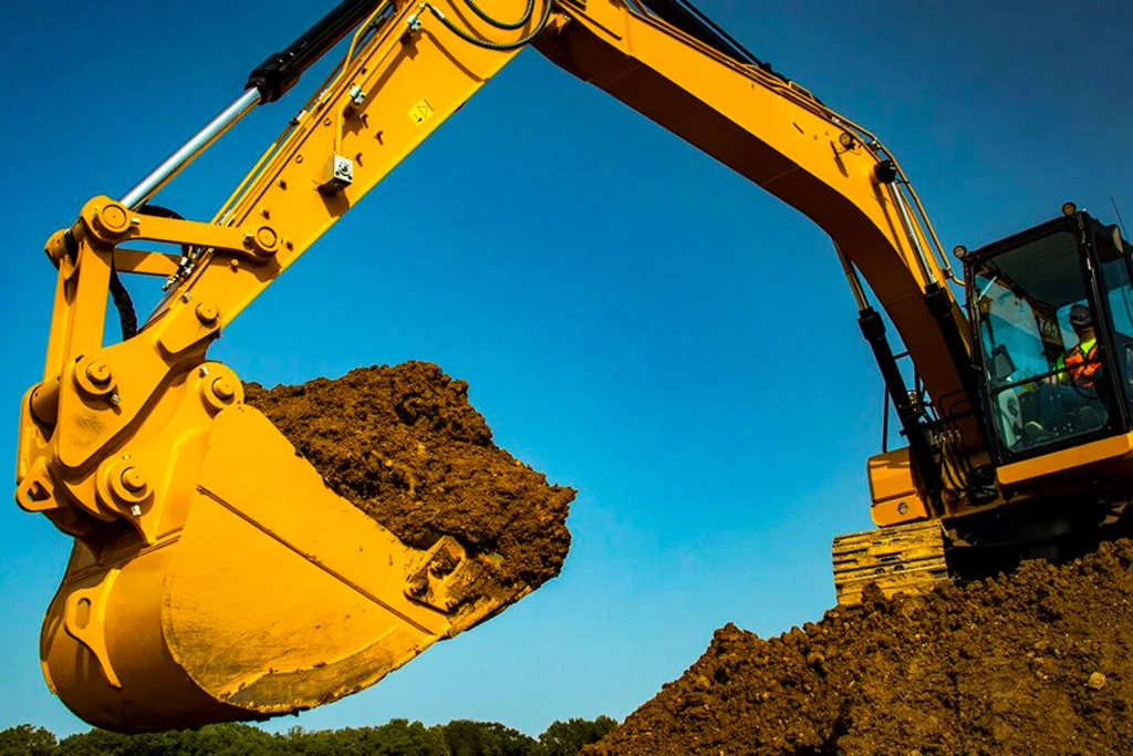 Excavator operator lifting a full bucket of dirt