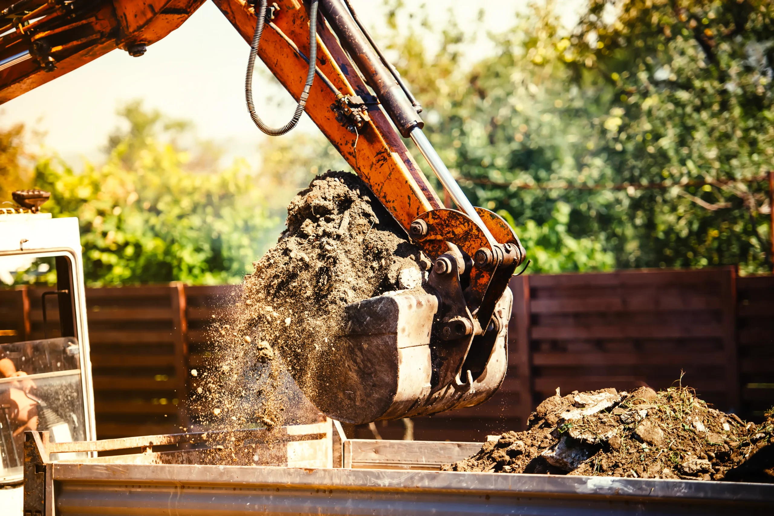 Excavator loading dirt and debris into a trailer