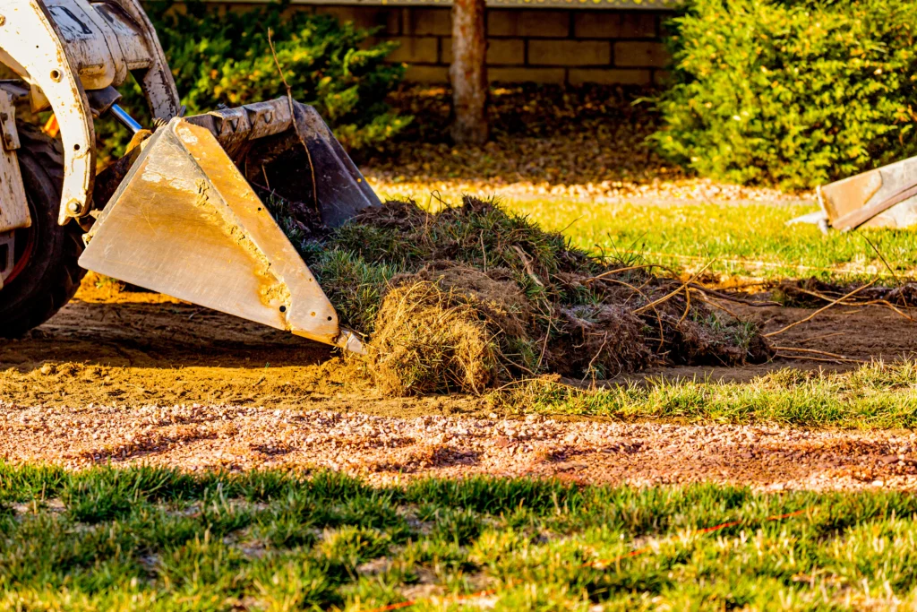 Skid steer removing sod and grass during yard preparation
